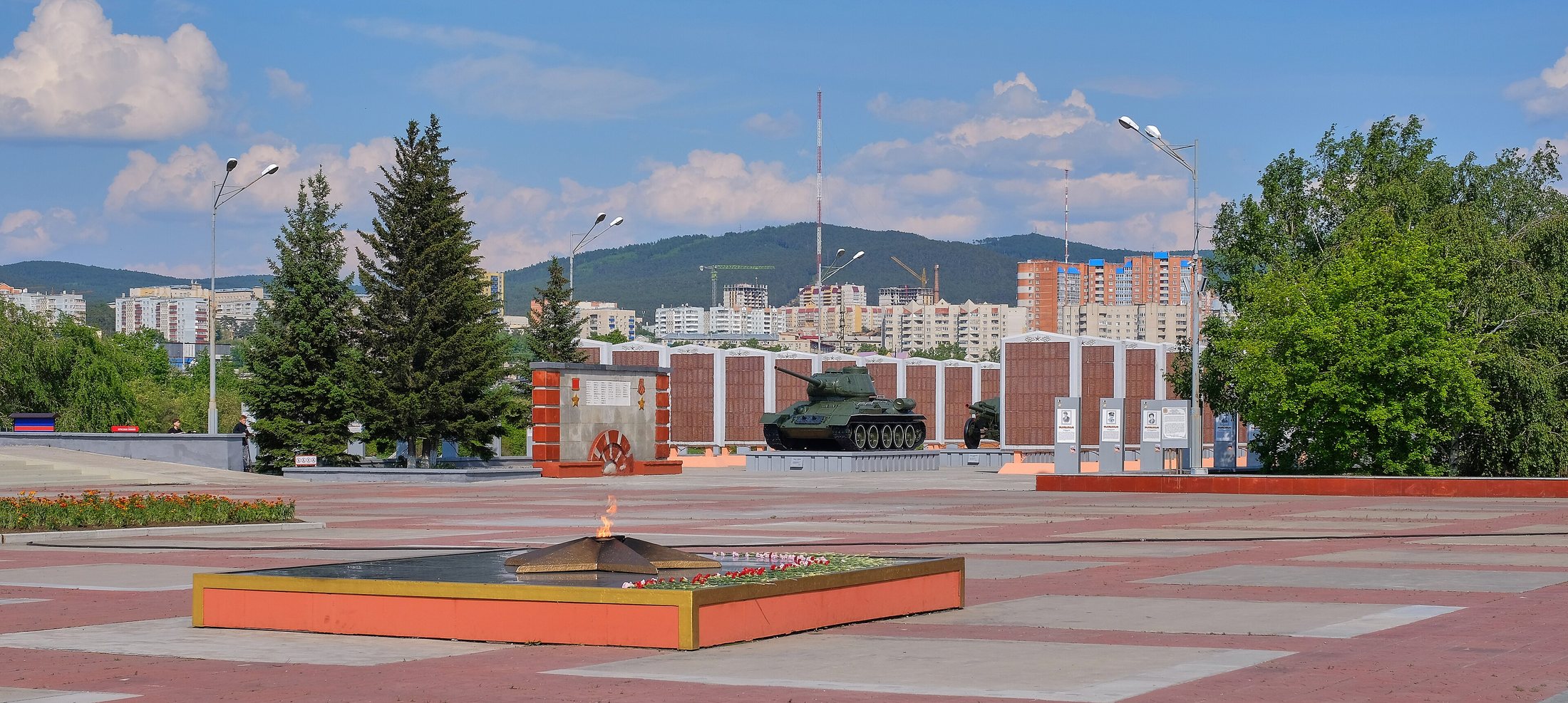 Вечный огонь сейчас: красно-серая плитка, оранжевое основание, вид на танк и стены с именами